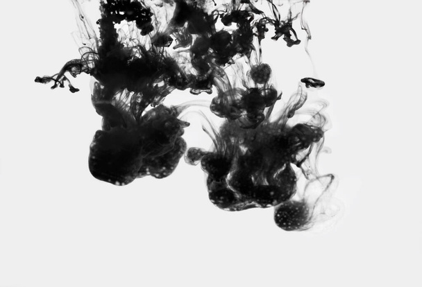 Encre noire tombée dans l'eau sur fond blanc, isolée - Photo, image