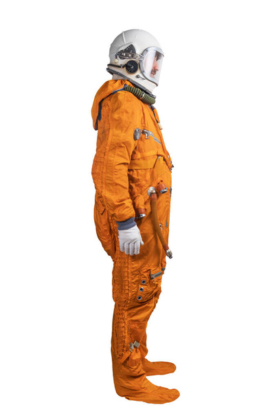 Astronaut wearing orange space suit and space helmet isolated on a white background. Side view - Фото, изображение