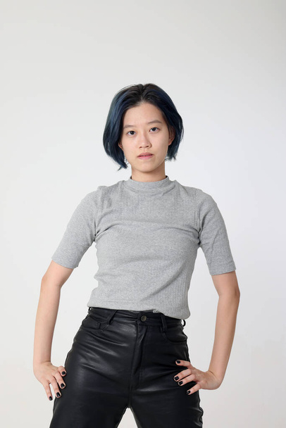 Молода приваблива азіатська жінка-підліток представляє режим вираження обличчя емоції на білому фоновому повороті моди - Фото, зображення