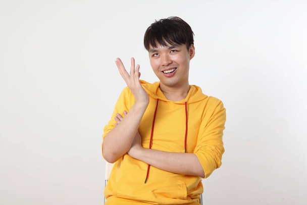 Young good looking Asian chinese malay man pose face body expression mode emotion on white background cross arm on chest look happy hand in air - Photo, Image