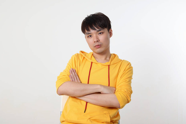 Jeune beau asiatique chinois malais homme pose visage corps expression mode émotion sur fond blanc croix bras sur poitrine regarder triste - Photo, image