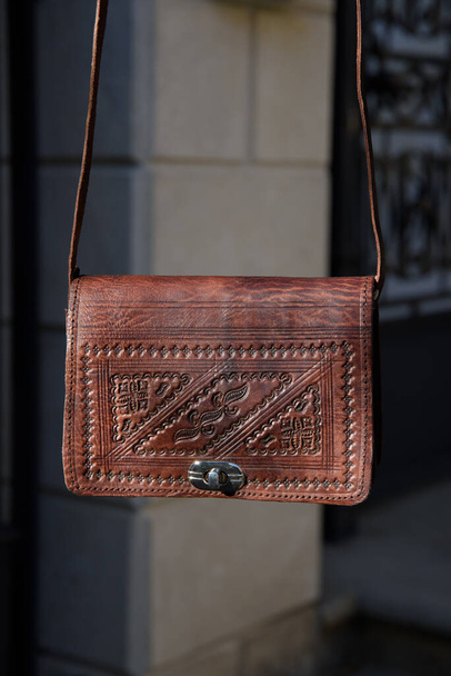 маленька коричнева жіноча шкіряна сумка з різьбленим візерунком
 - Фото, зображення