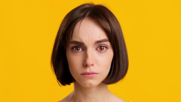 Smutná mladá dáma pláč pocit nešťastný pózování přes žluté pozadí - Záběry, video