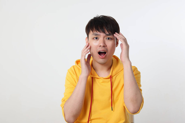 Молодой симпатичный азиатский китайский малайзийский мужчина представляет лицо режим выражения эмоций на белом фоне мотылька открытым криком удивлена рука - Фото, изображение
