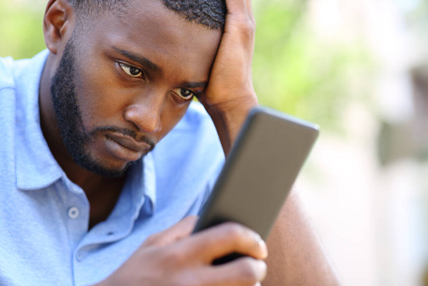 Worried man with black skin checking smart phone content in the street - Φωτογραφία, εικόνα