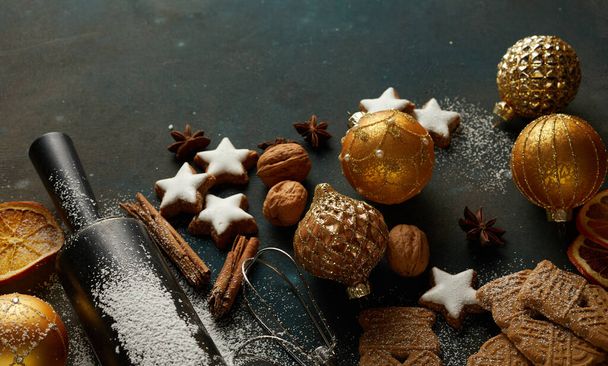 Composition with Christmas cookies, baubles, cinnamon sticks, nuts, and baking tools on the table - Foto, Imagem