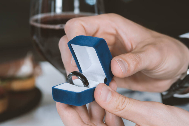 Male hands with blue velvet box containing payments smart ring. Man gives a woman payments smart ring.  Romantic dinner. Valentine day - Fotografie, Obrázek