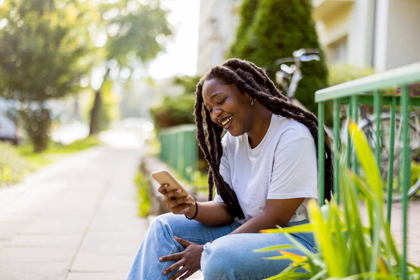 Mujer joven atractiva usando su teléfono inteligente al aire libre - Foto, imagen