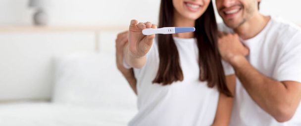 Невідомий щасливий молодий кавказький чоловік і леді радіють результату і показують тест на вагітність
 - Фото, зображення