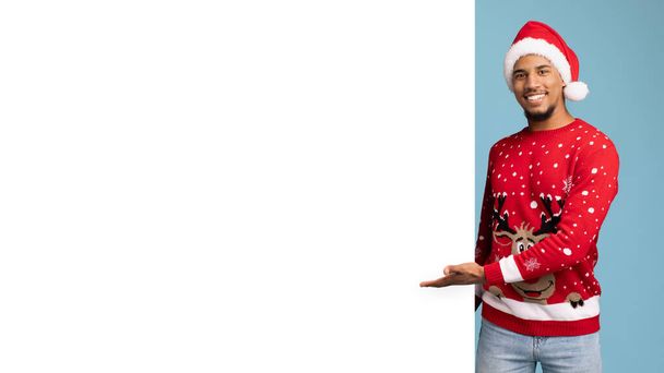 Fröhlicher afrikanisch-amerikanischer Weihnachtsmann steht neben leerem Plakat, Panorama - Foto, Bild