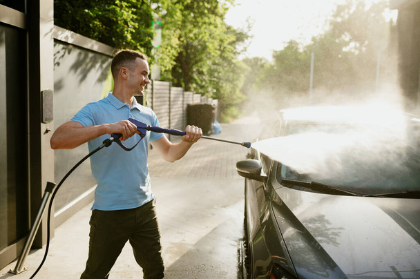 Mężczyzna trzyma pistolet wodny wysokiego ciśnienia, mycie automatyczne - Zdjęcie, obraz