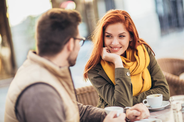 Attractive young couple in love sitting at the cafe table outdoors, drinking coffee - Φωτογραφία, εικόνα