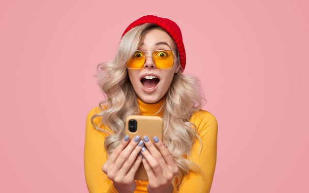 Shocked woman in colorful sunglasses reacting to message on smartphone - Foto, immagini