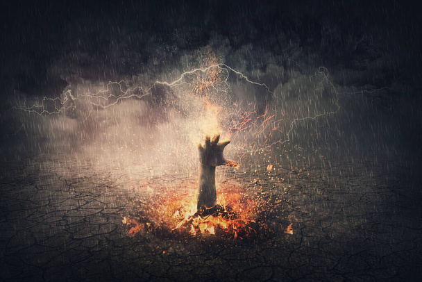 Kéz a tűzben emelkedik ki a földből. Szürreális jelenet lángoló démoni karral a pokolból. Halloween koncepció, kísérteties háttér - Fotó, kép