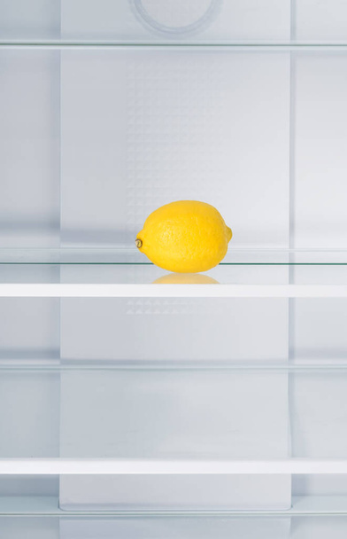 in einem leeren Kühlschrank steht eine Zitrone im Regal - Foto, Bild