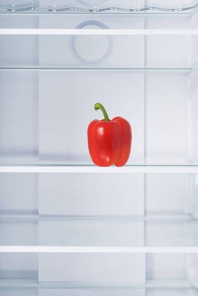 there is red bell pepper on the shelf in an empty refrigerator - 写真・画像