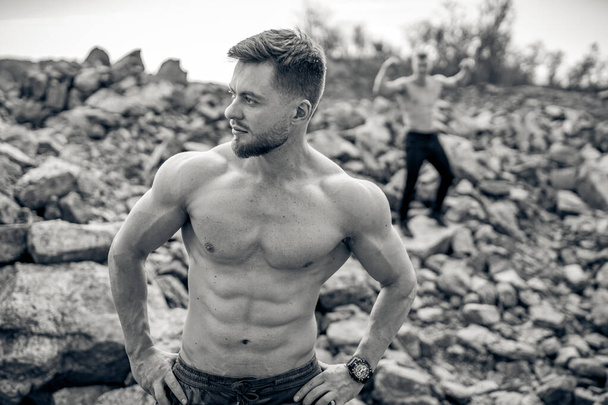 Healthy sporty bodybuilder in good shape showing his torso. Strong muscular shirtless man standing outdoor. - Fotografie, Obrázek