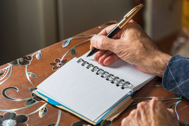 Человек собирается написать что-нибудь на листе бумаги чернильной ручкой - Фото, изображение