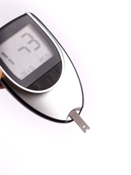 Krevní glukózoměr, hladina cukru v krvi se měří na prstu na bílém pozadí. - Fotografie, Obrázek
