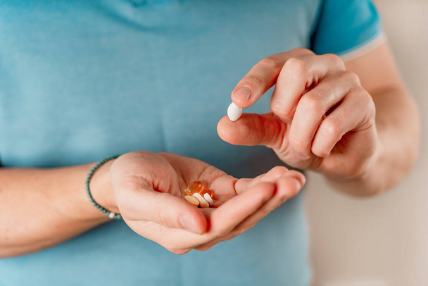 Az az ember tablettákat és kapszulákat tart a kezében. Vitaminok és gyógyszerek szedése, közelről - Fotó, kép