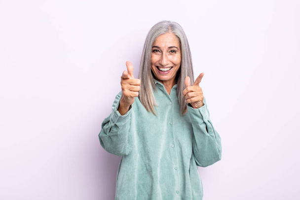 middle age gray hair woman feeling happy, cool, satisfied, relaxed and successful, pointing at camera, choosing you - Foto, Imagen