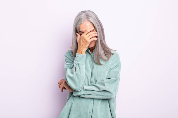 middle age gray hair woman looking stressed, ashamed or upset, with a headache, covering face with hand - Foto, Imagem