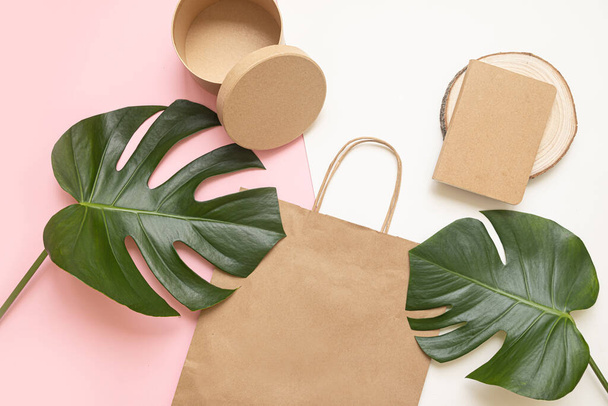 Flat Lay shopping concept met papieren tas en tropische bladeren. Elegante compositie met elegante accessoires. - Foto, afbeelding