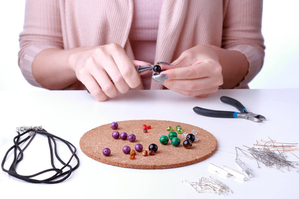 Zbliżenie żeńskich dłoni. Kobieta pracuje z narzędziami jubilerskimi na białym tle. Projektant biżuterii pracuje w studio z narzędziami wykonującymi biżuterię.  - Zdjęcie, obraz