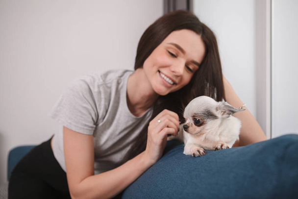 Gyönyörű boldog nő simogatja imádnivaló kis kutyáját, otthon marad - Fotó, kép