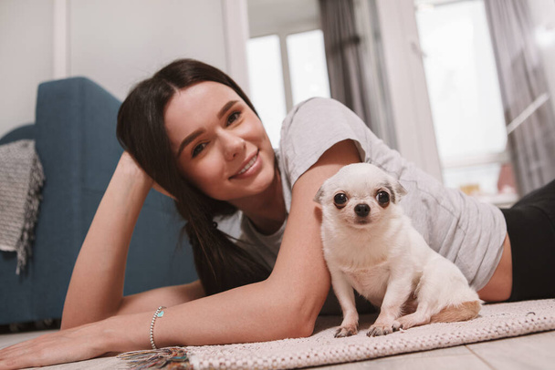 Muhteşem mutlu kadın ve onun chihuahua köpeği kameraya bakıyor, evde dinleniyor. - Fotoğraf, Görsel