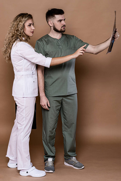 Nuoret lääkärit, joilla on tavallinen tausta lääketieteellisissä vaatteissa. He keskustelevat aivojen kuvantamistiedoista yhdessä.. - Valokuva, kuva
