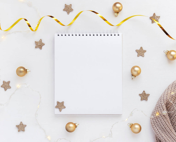 星、クリスマスボールやお祝いの庭と白いテーブルの上にノートブックのホワイトシート。コンセプト企画、新年の願い事リスト. - 写真・画像