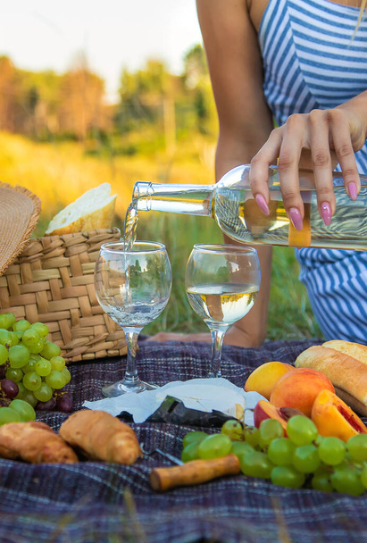 Das Mädchen schenkt Wein bei einem Picknick ein. Selektiver Fokus. Natur. - Foto, Bild