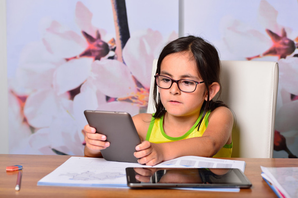 Little girl using a Tablet PC and an Ebook for homework - Fotografie, Obrázek