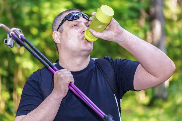 Man with water bottle and walking sticks - Photo, Image