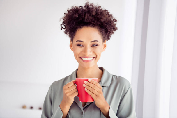 Photo of young cheerful afro girl awakening good mood drink delicious coffee tea latte wear silky pajama indoors - Photo, Image