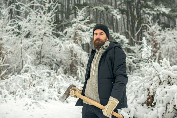 Man lumberjack with axe outdoor in winter. Bearded man with axe in snowy forest. - Foto, afbeelding