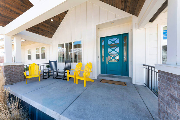 Portico di una casa con porta verde blu e sedie a sdraio - Foto, immagini