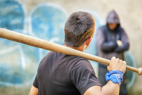 agressieve tiener met een honkbalknuppel tegen man op buiten - Foto, afbeelding