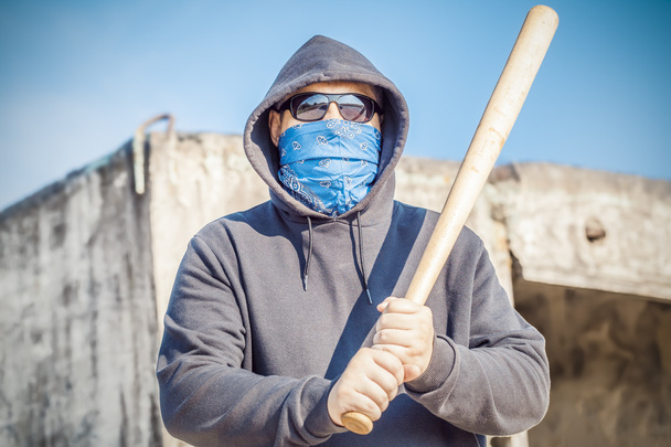 Aggressive man with a baseball bat on building background - Photo, Image