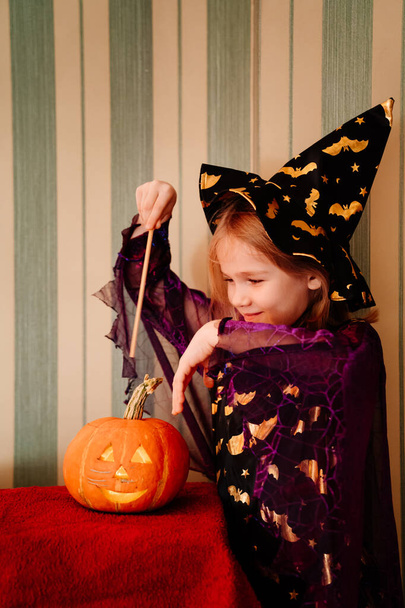 a little girl in a masquerade witch costume with a pumpkin lantern for Halloween - Foto, immagini