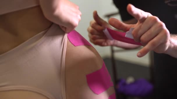 Fizioterapeuta kinesio szalagot alkalmaz női betegen. - Felvétel, videó
