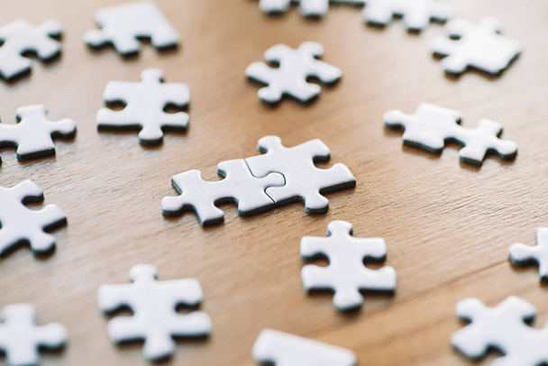  Puzzle pieces are connected. White puzzle pieces on a wooden table background. Business, partner, solution, alliance, union concept. - 写真・画像