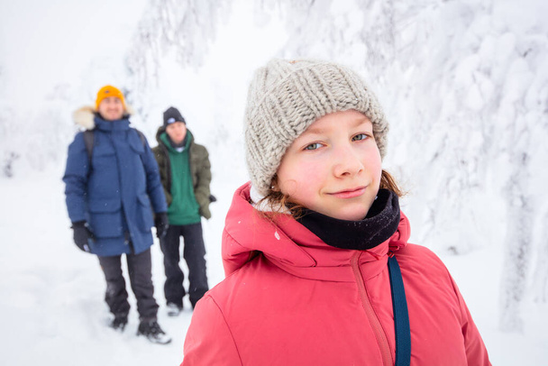 Portrait of beautiful teenage girl and her family in snow covered winter forest in Lapland Finland - Foto, Imagem