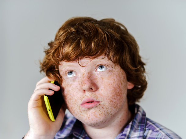 Koominen pisamainen punatukkainen poika matkapuhelimella
 - Valokuva, kuva