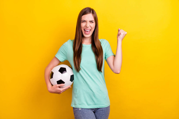 Photo of hooray brunette hairdo young lady hold ball wear teal t-shirt isolated on yellow color background - Valokuva, kuva