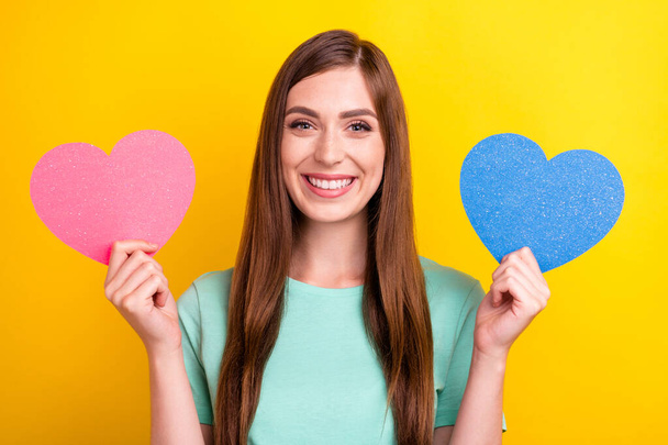 Kuva funky brunette hairdo nuori nainen pidä sydämet kulumista sinivihreä t-paita eristetty keltainen väri tausta - Valokuva, kuva