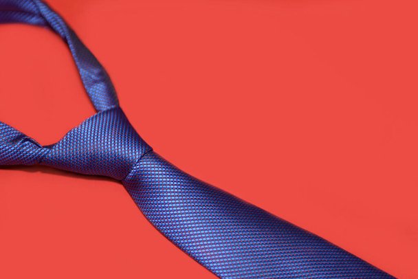 Corbata azul sobre fondo escarlata. Accesorio masculino primer plano. - Foto, Imagen