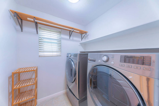 Small white laundry room interior with wooden shelves and floor rack - Photo, Image