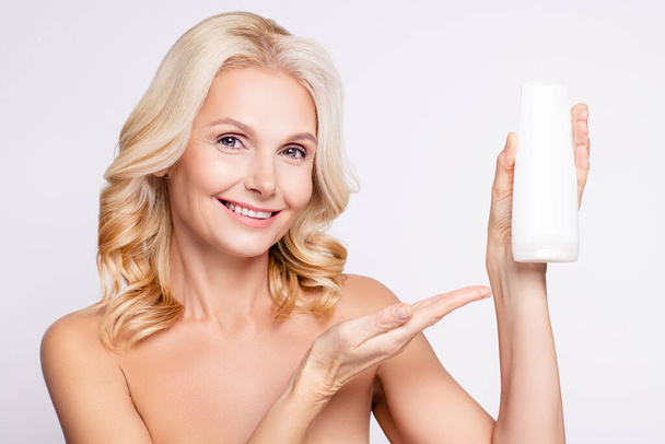 Photo of cute blond hairdo aged lady hold shampoo without clothes isolated on white color background - Zdjęcie, obraz